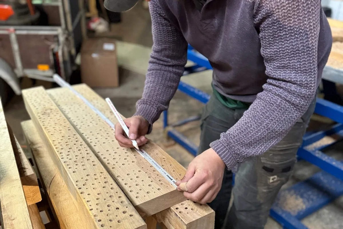 Mitarbeiter beim Vermessen gebohrter Holzblöcke für Wildbienen-Nisthilfen in der eigenen Werkstatt.